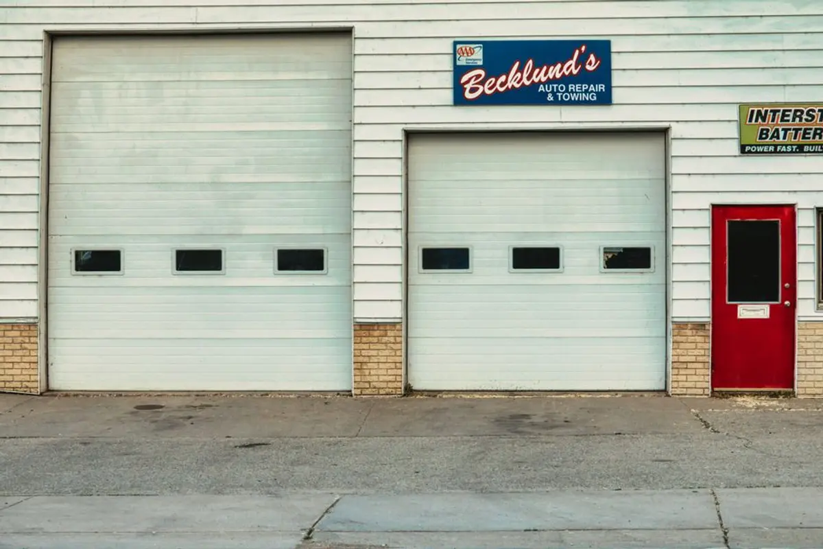 Devanture d'un local commercial vide avec rideau de fer baissé, rue commerçante en journée